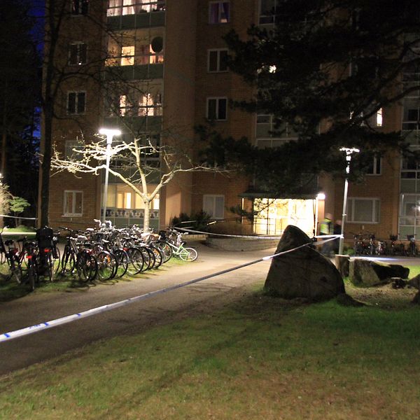 Polisavspärrningar vid ett lägenhetshus på kvällen.