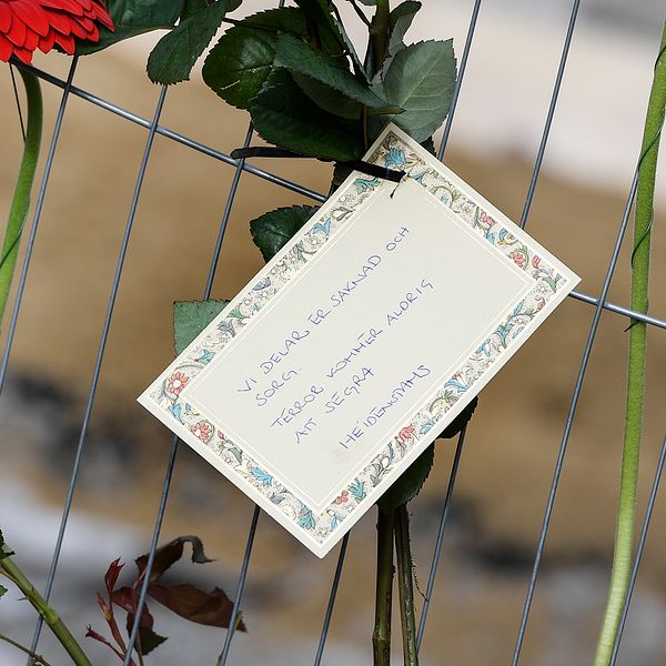 Blommor och ett kort med texten ”Vi delar er saknad och sorg. Terror kommer aldrig att segra. Heidenstams”