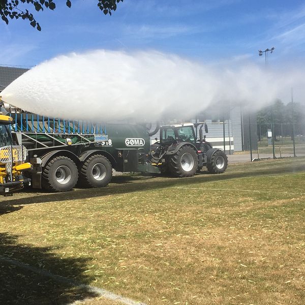 Tankbil sprutar vatten på planen vid Kombihallen på Halmstad Arena.