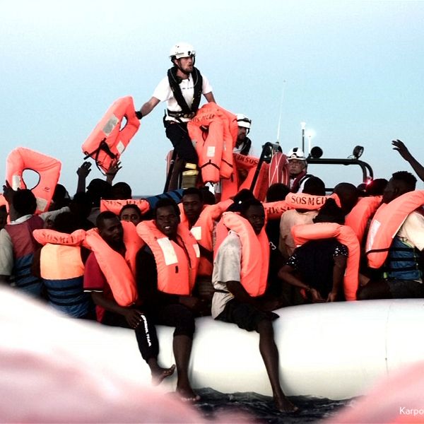 Flera personer i flytväst ombord en vit gummibåt ute till havs.