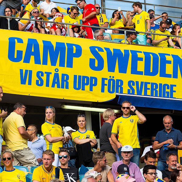 Fullt med fans klädda i svenska gulblå matchtröjor på en fotbollsläktare.