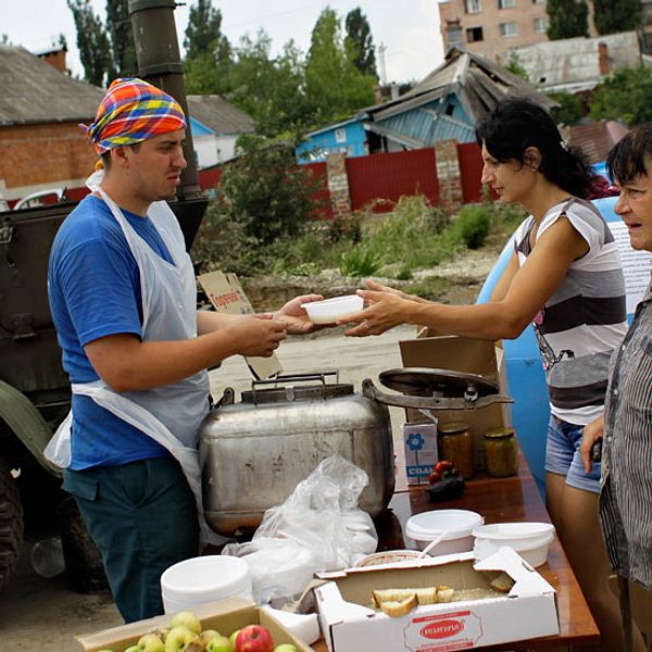 En hjälparbetare delar ut mat och vatten till invånare som drabbats av översvämningen i staden Krymsk.