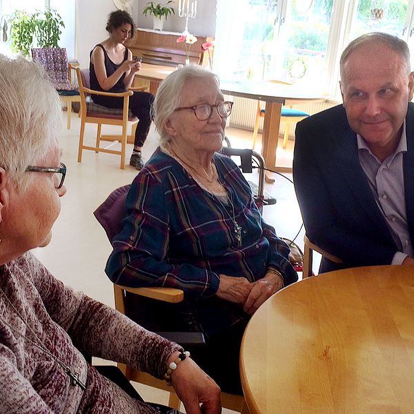 Jonas Sjöstedt sitter tillsammans med två äldre damer vid ett runt bord.