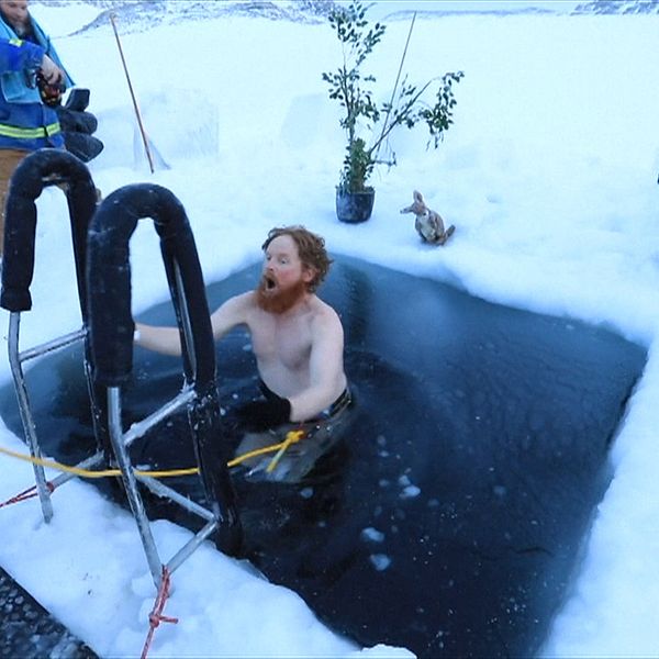 Man kliver ned för stege till öppet vatten i en isvak.