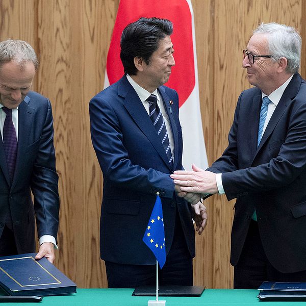 Japans premiärminister Shinzo Abe, i mitten, skakar hand med EU-kommiussionens ordförande Jean-Claude Junker efter att ha skrivit under frihandelsavtalet på tisdagen.