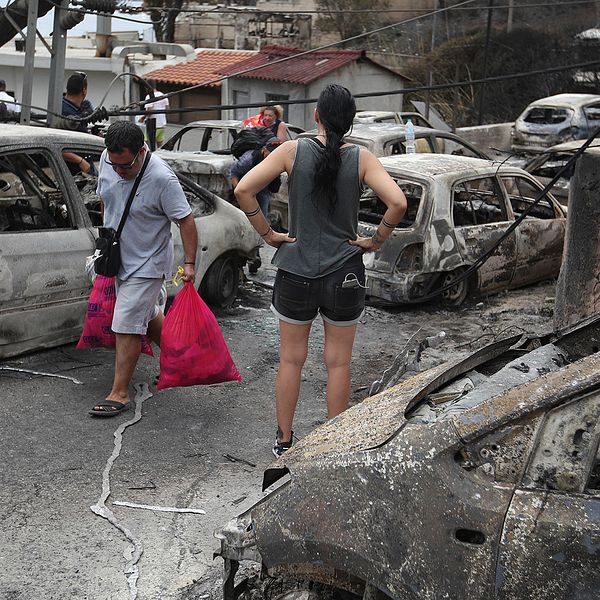 Kvinna står och tittar ut över ruinerna i staden Mati som drabbats hårt av bränderna