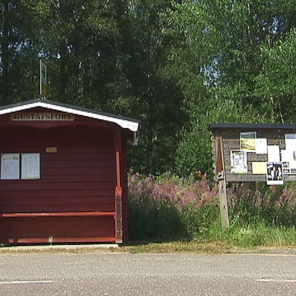 rödtimrad väntkur med Gustavsfors-skylt samt anslagstavla bredvid