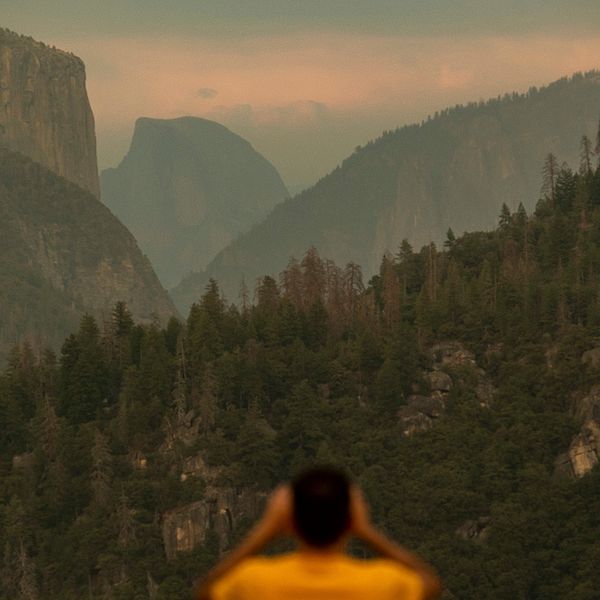 En man tittar ut över nationalparken Yosemite och man ser rök vid bergstopparna.
