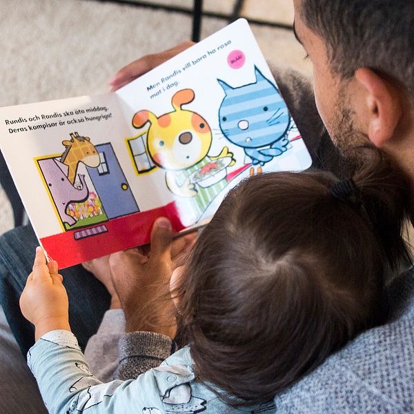 Pappa som läser i barnbok för sitt barn