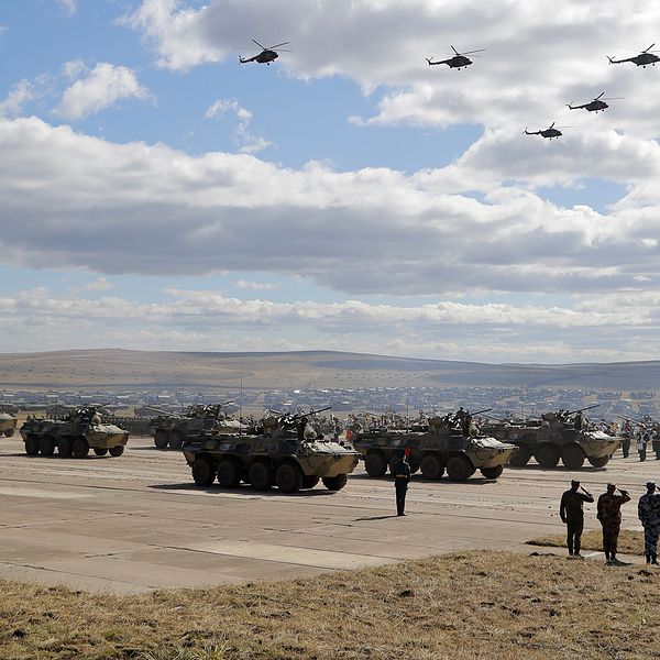 En stor militärövning med stridsvagnar, helikoptrar och infanterister på ett fält.