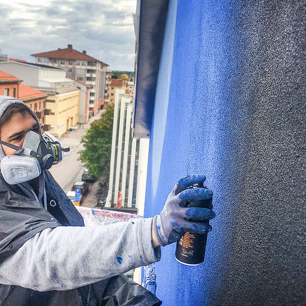 Assistenten Filip arbetar 16 meter upp i en skylift med muralmålningen som tar form på Södermalmstorg.