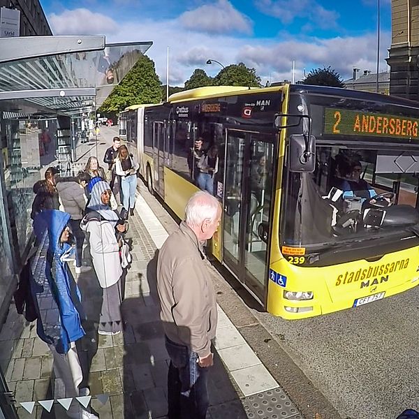 Stadsbuss i Gävle stannar vid hållplats i centrum där passagerare väntar på att stiga på.