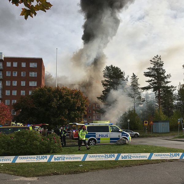 avspärrning, polisbilar och folk vid tegelhus, stor rökpelare