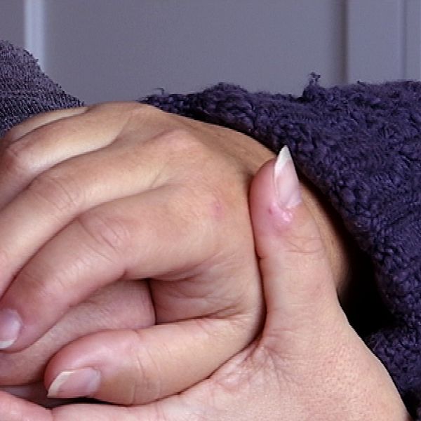 En kvinna kramar sin mammas gamla hand.