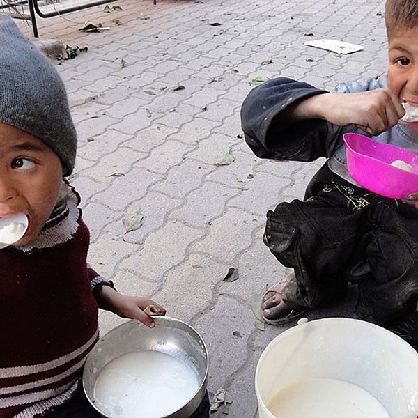 Två barn äter mat som delats ut till dem i flyktinglägret i Yarmouk i Damaskus. Bilden är tagen den sjunde april, och sedan den nionde har ingen hjälpsändning nått fram till lägret, där 20.000 Syrienflyktingar bor.