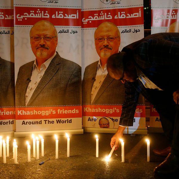 En man tänder ljus framför porträtt av saudiske journalisten Jamal Khashoggi, som misstänks ha mördats.