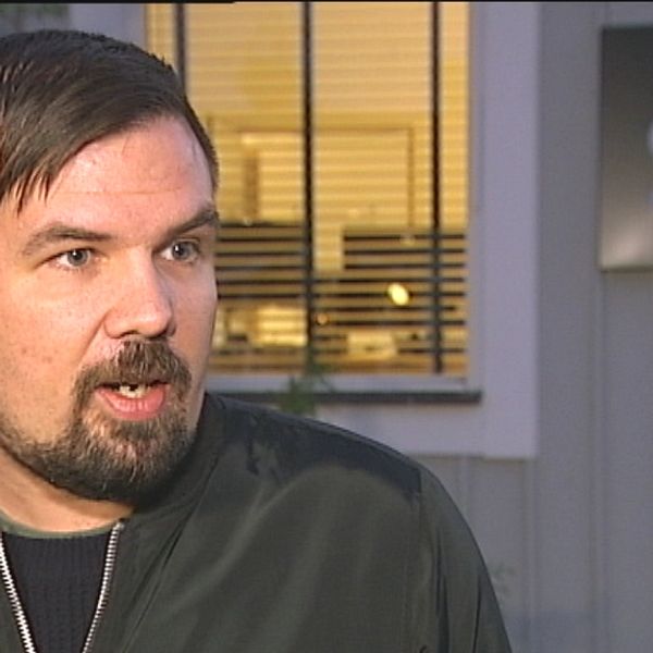 Philip Naskret, reporter på SVT, utanför hus med SVT-logga