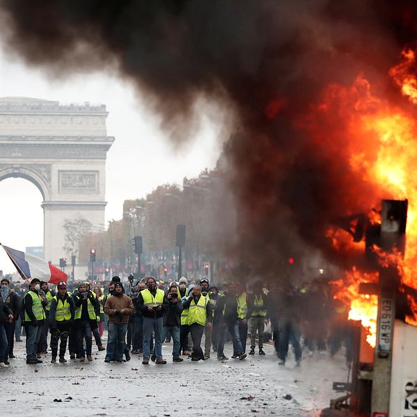 Demonstranter i gula västar protesterar mot Franrikes president Emmanuel Macron. På bilden syns en brinnande lastbil och triumfbågen.