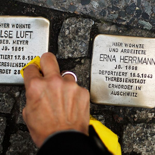 En hand putsar gatustenar till minne av de som dödades under Nazityskland.
