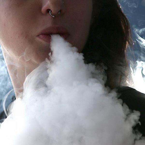Ung kvinna röker e-cigarett.