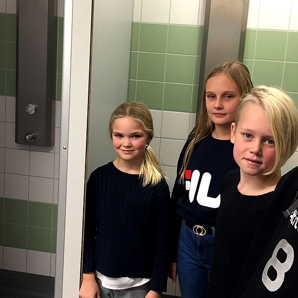 Flera barn står vid dusch med draperi