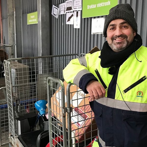 Rickard Hagman i reflexjacka framför en bur med elektronikskräp.