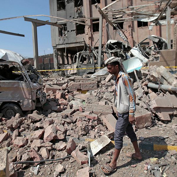 En man går i rasmassorna till ett hus i Jemen.