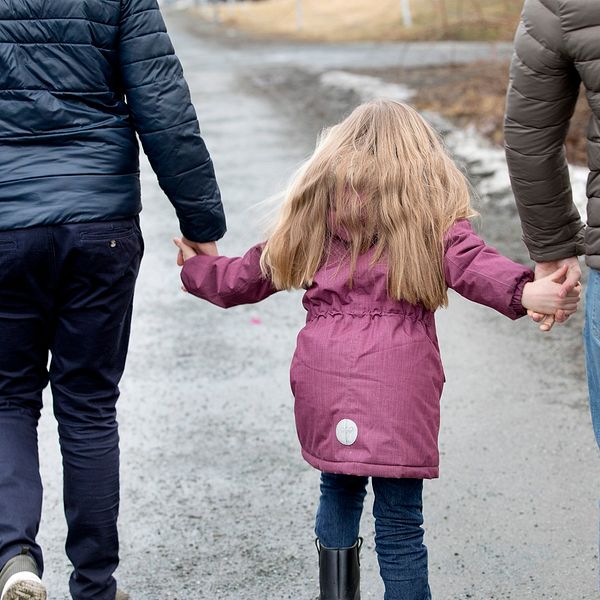 Föräldrar som går med barn i handen.