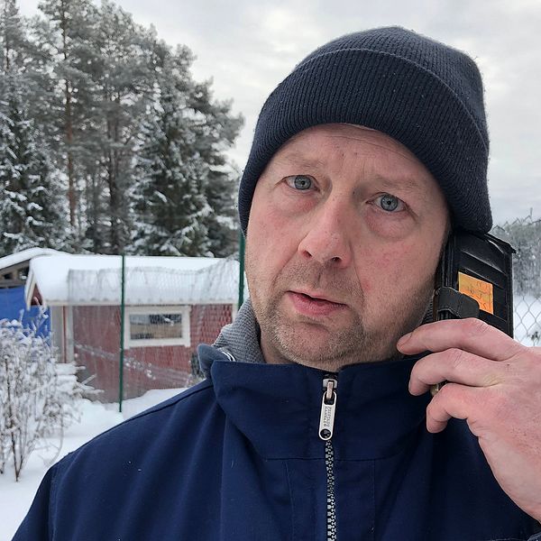 en man som pratar i mobilen, utomhus på snöig gård