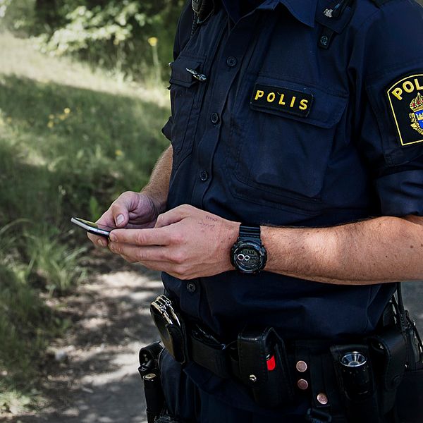 En polis står med en mobiltelefon.