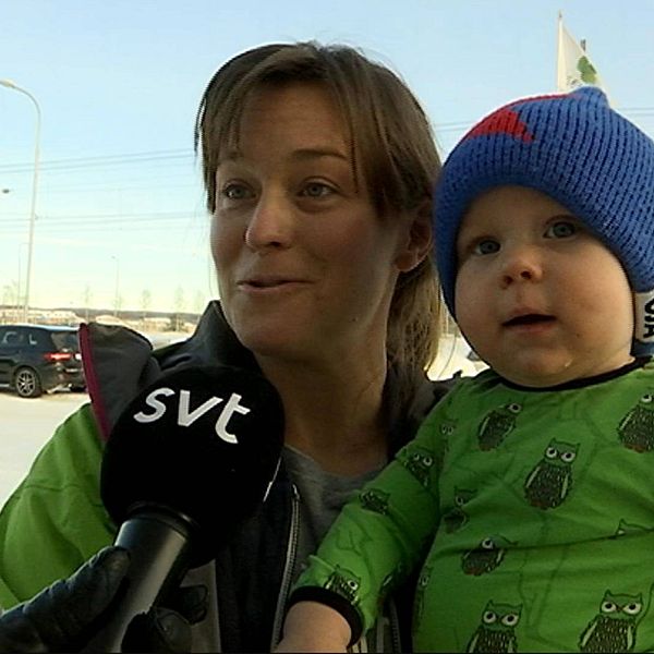 en kvinna med liten pojke i famnen intervjuas ute vintertid