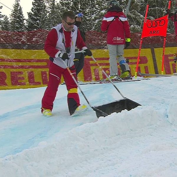 man i rödvita kläder skottar snö i skidbacke i Åre under alpina VM 2019