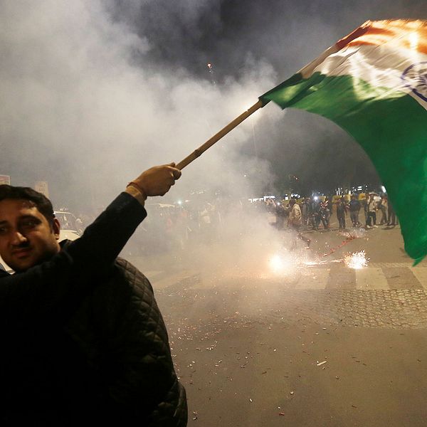 En man håller en indisk flagga under firandet efter att indiska myndigheter rapporterade att de flygbombat ”terrorläger”