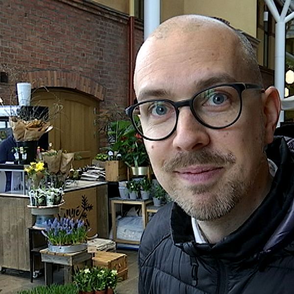 En man med glasögon vid en blomsteraffär