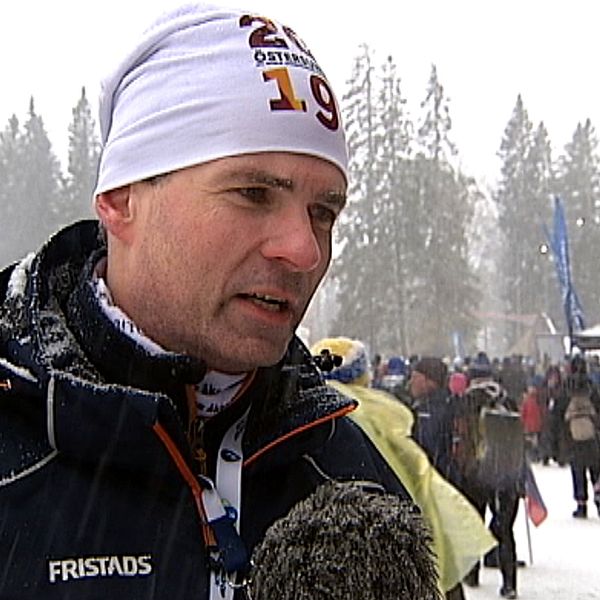Patrik Jemteborn, VM-general för skidskytte i Östersund står i blå jacka och vit mössa i snöfall.