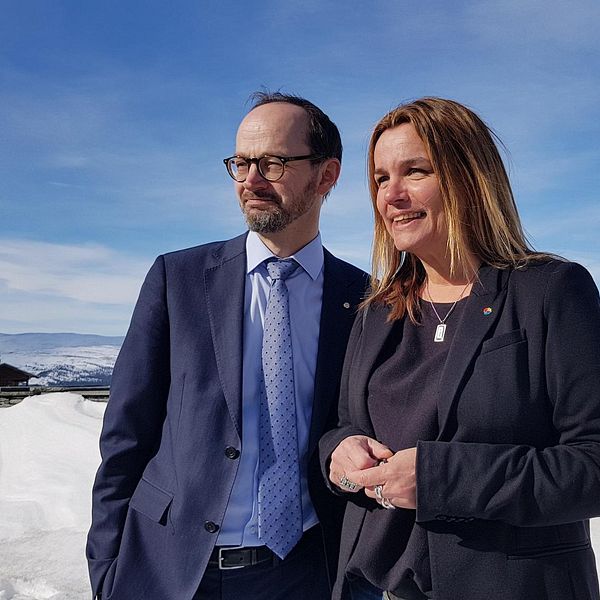 En man (infrastrukturminister Tomas Eneroth) och en kvinna (riksdagsledamoten Anna-Caren Sätherberg) står i solen i Åre och tittar åt vänster.