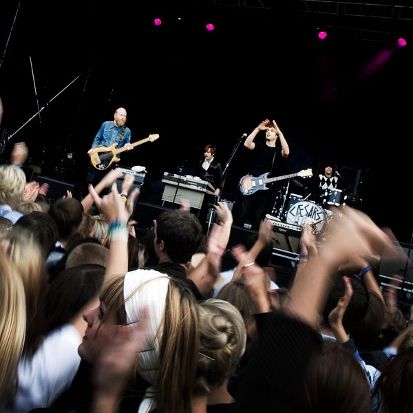 Publik som dansar framför en scen vid en konsert.