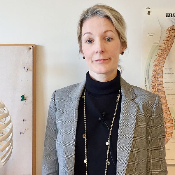 Sandra Schönbeck bredvid ett skelett och en plansch om ryggskador.