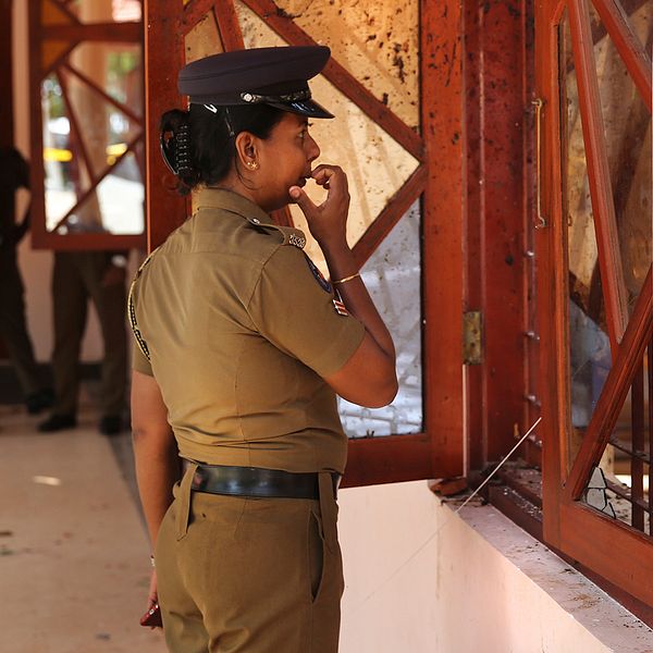 Poliskvinna i Sri Lanka tittar in i en av kyrkorna som attackerades i terrordåden.
