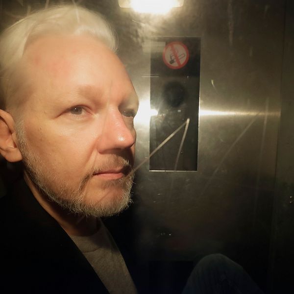 Julian Assange fotograferad genom rutan på en bil utanför domstolen i London.