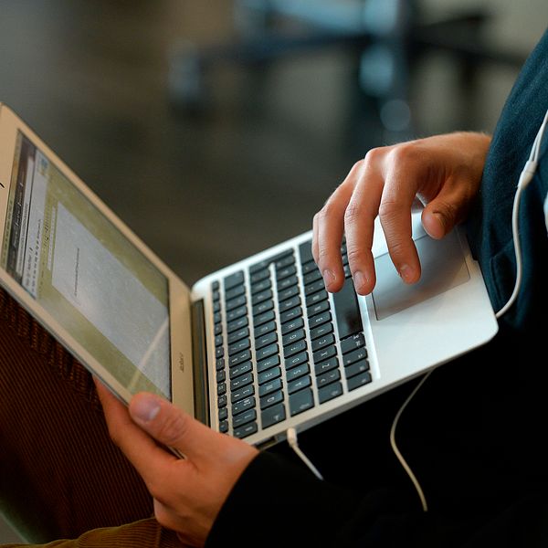 En elev sitter med en dator i knät.