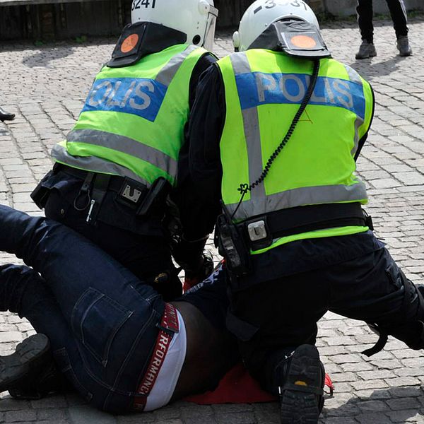 Två polis håller ner en demonstrant.