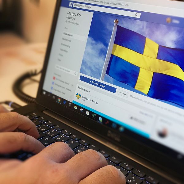 En person skriver på sin laptop. På skärmen syns svenska flaggan som används som bakgrundsbild i Stå upp för Sverige-gruppen på Facebook.