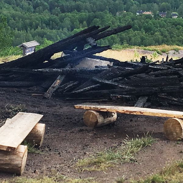 En hög svartbränt virke. Svag rök stiger från resterna efter konstverket ”Waaall”.