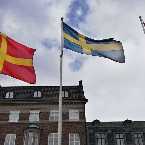 Två skånska rödgula flaggor vajar på varsin sida om den svenska flaggan på Stortorget i Lund, då det under dagen firades Skåneländska flaggans dag.