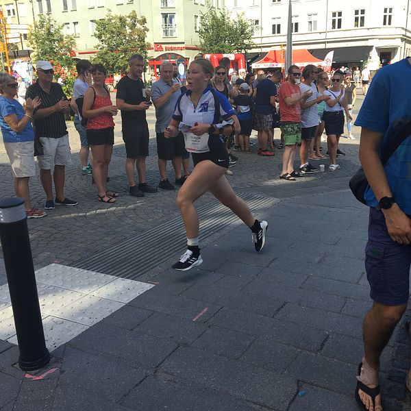 En orienterarer springer på en gata i Norrköping medan folk står och klappar i händerna.