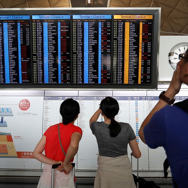 Passagerare kollar på avgångstavlan på Hongkongs flygplats.