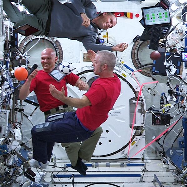 Tre astronauter svävar i luften inne på rymdstationen ISS.