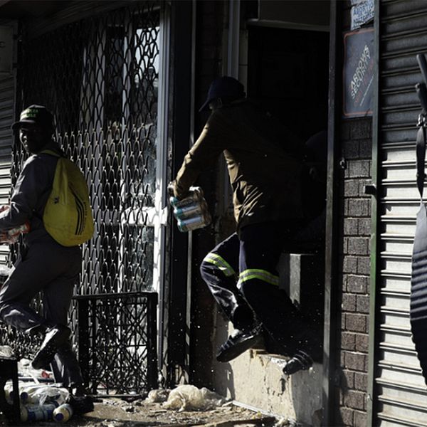 Plundrare som lyckas få med sig varor från en butik i Germiston öster om Johannesburg samtidigt som den sydafrikanska polisen närmar sig.