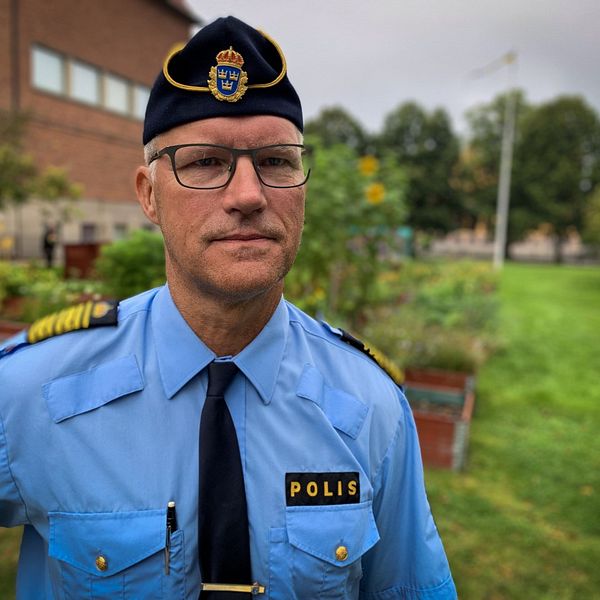 Polis står framför blomodlingar.